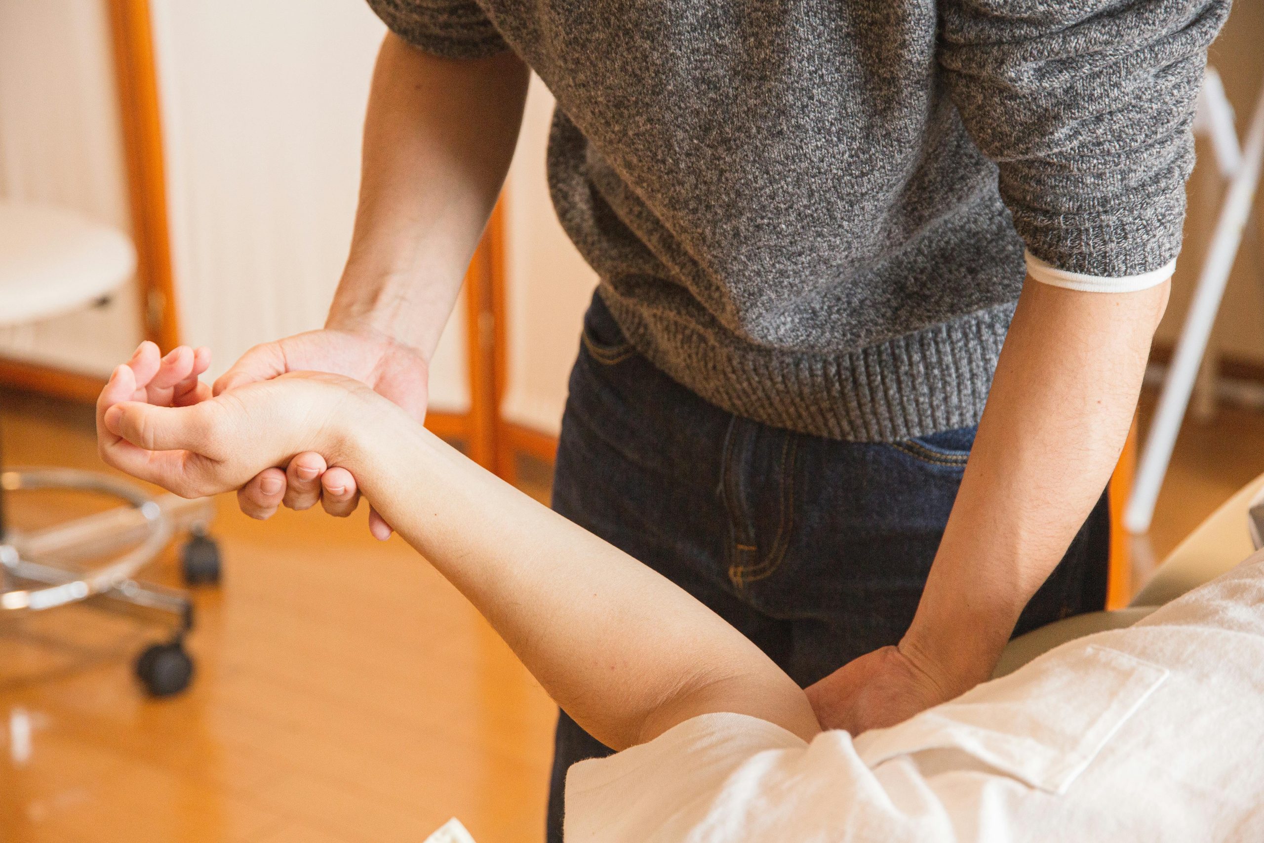 Occupational Therapist Helping a Consumer with Excercise Therapist assisting a patient with wrist therapy. Focus on healthcare and wellness.